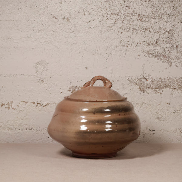 Ceramic pot with a lid on a textured surface