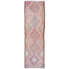 A long rectangular runner rug with a vintage geometric kilim pattern in shades of pink, beige, and light blue on a white background.