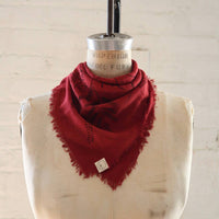 Red scarf on a mannequin bust against a white brick wall.