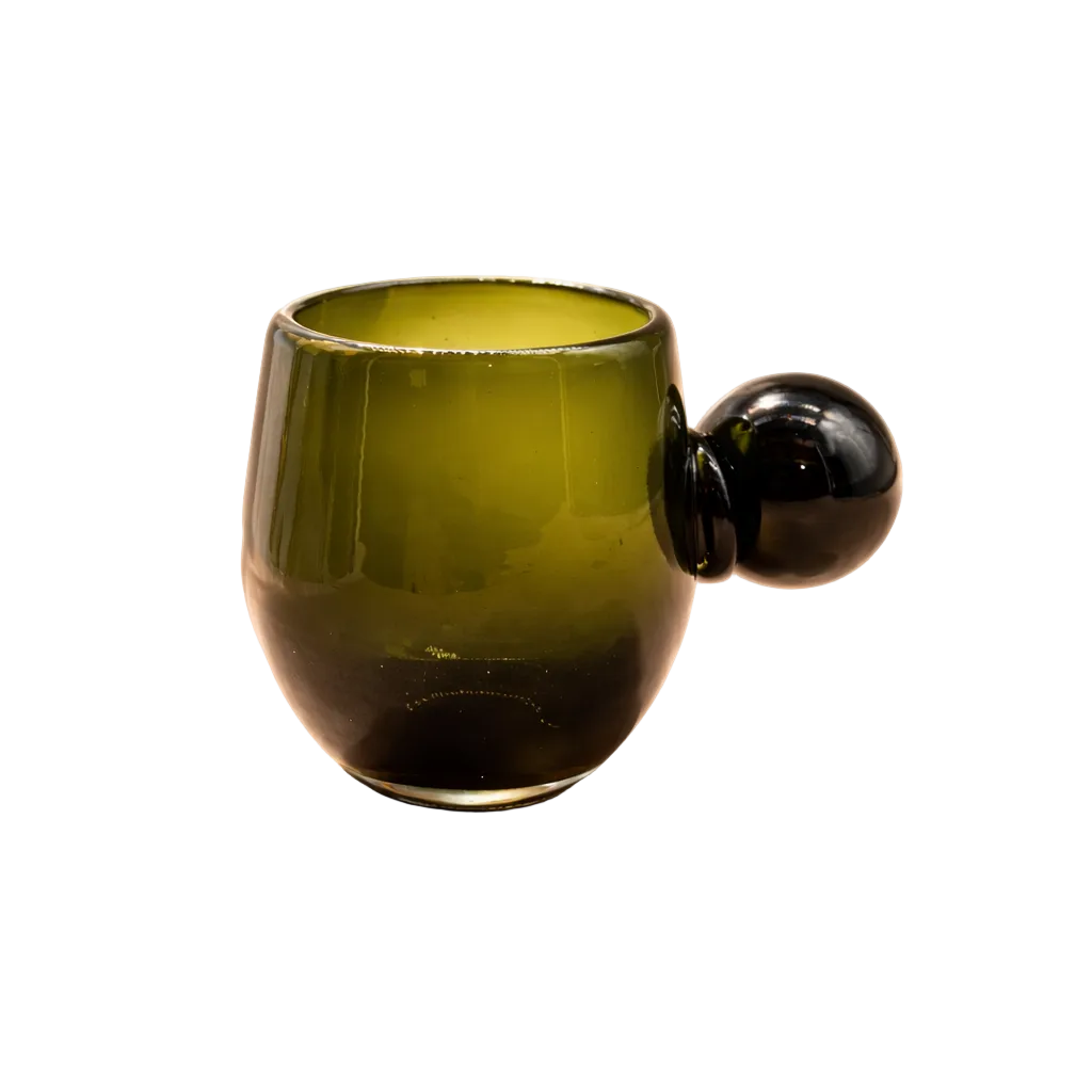 Green glass mug with black handle on a beige background