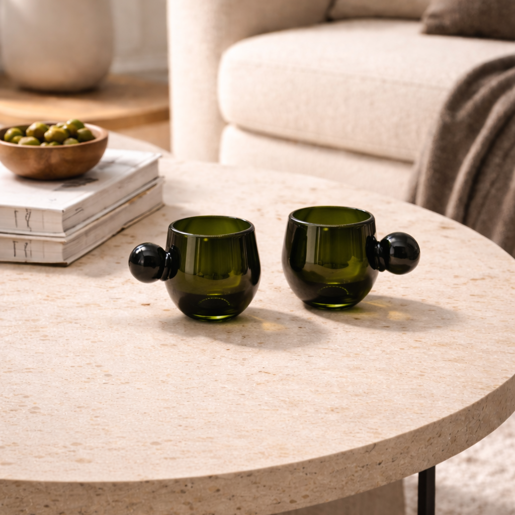Two green ceramic cups on a light wood coffee table in a living room setting.