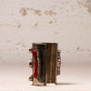 A vintage silver-toned cuff bracelet with red enamel inlays and silver-toned metal accents, displayed on a light textured surface against a neutral background.