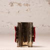 A vintage silver-toned cuff bracelet with red textured inlay panels on both sides, displayed against a textured off-white background.