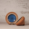 Ceramic bowl with blue interior and brown exterior on a textured surface