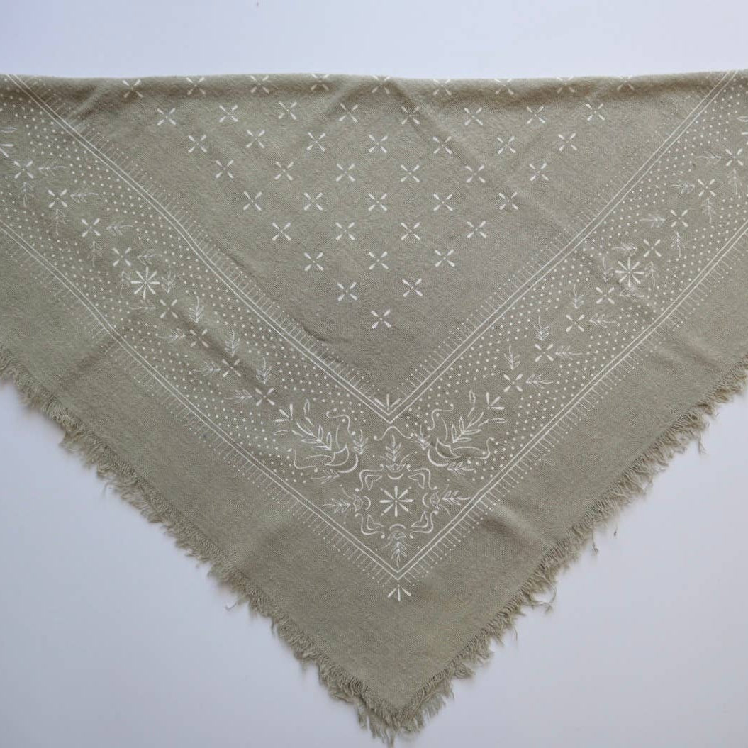 Green triangular scarf with embroidered pattern on a white background