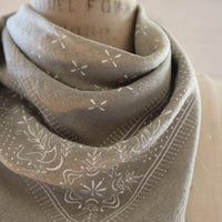 Gray scarf with floral patterns draped over a surface