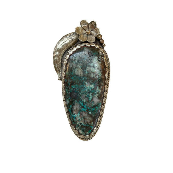 Jewelry piece with a large stone and floral design on a white background