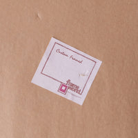 A small white square card with a pink border and the words 'Custom Framed' and the frame world logo, placed on a brown kraft paper background.