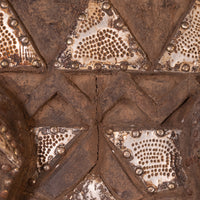 Close-up of a textured metal surface with geometric riveted panels in brown and silver tones.