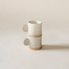 White ceramic cup with unglazed base on a beige background