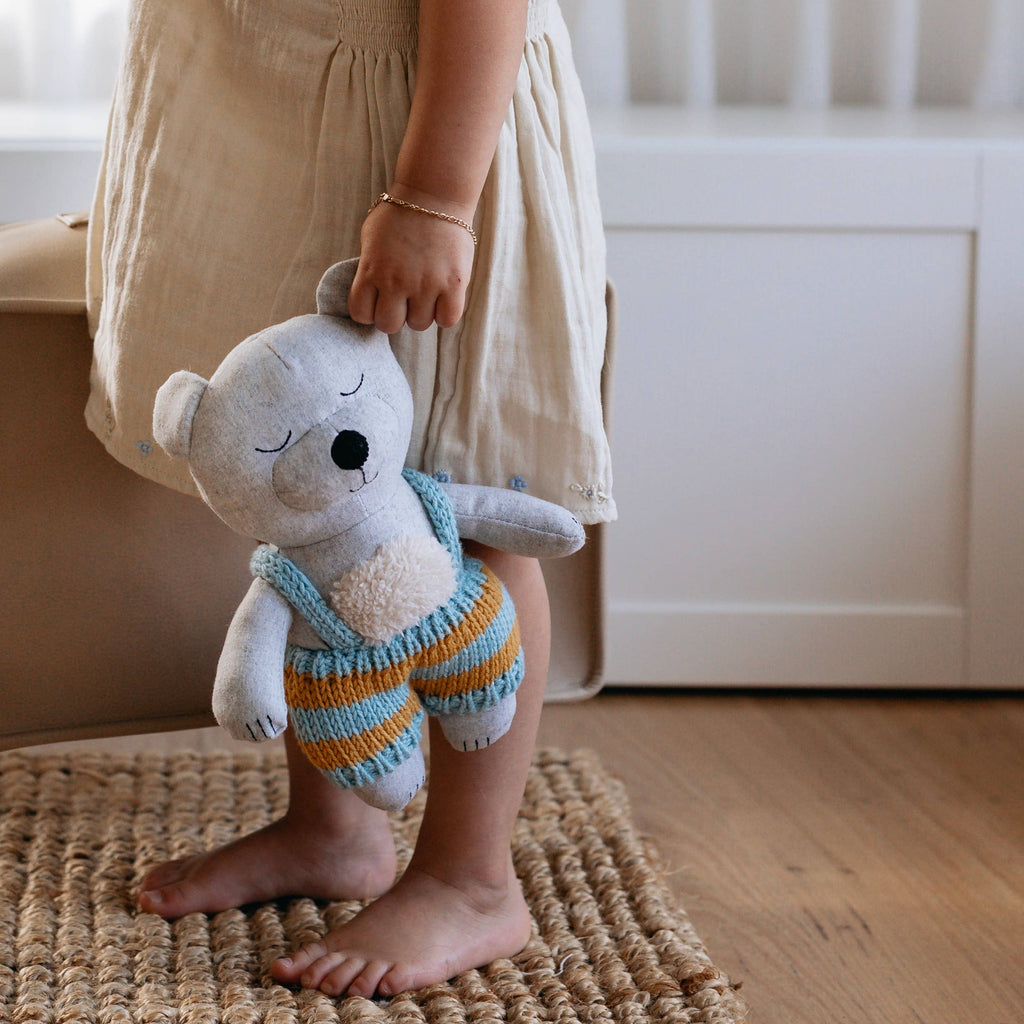 Spencer Bear in blue being held by a child 