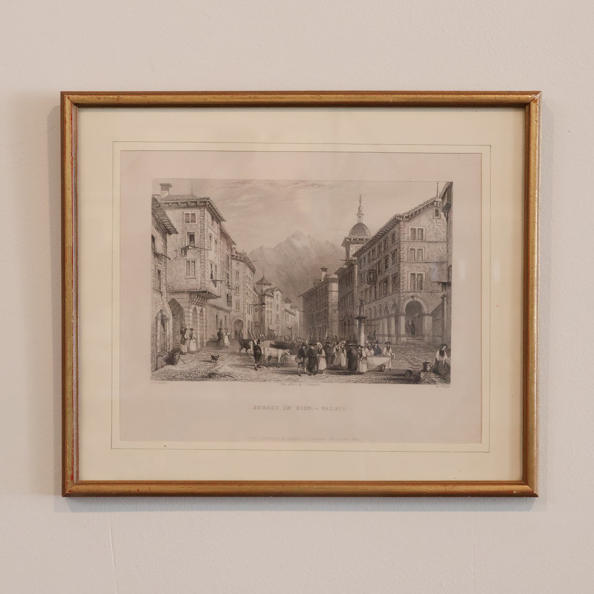 Framed black and white print of a city street scene on a beige wall.
