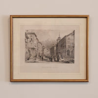 Framed black and white print of a city street scene on a beige wall.
