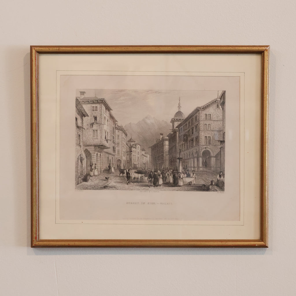 Framed black and white print of a city street scene on a beige wall.