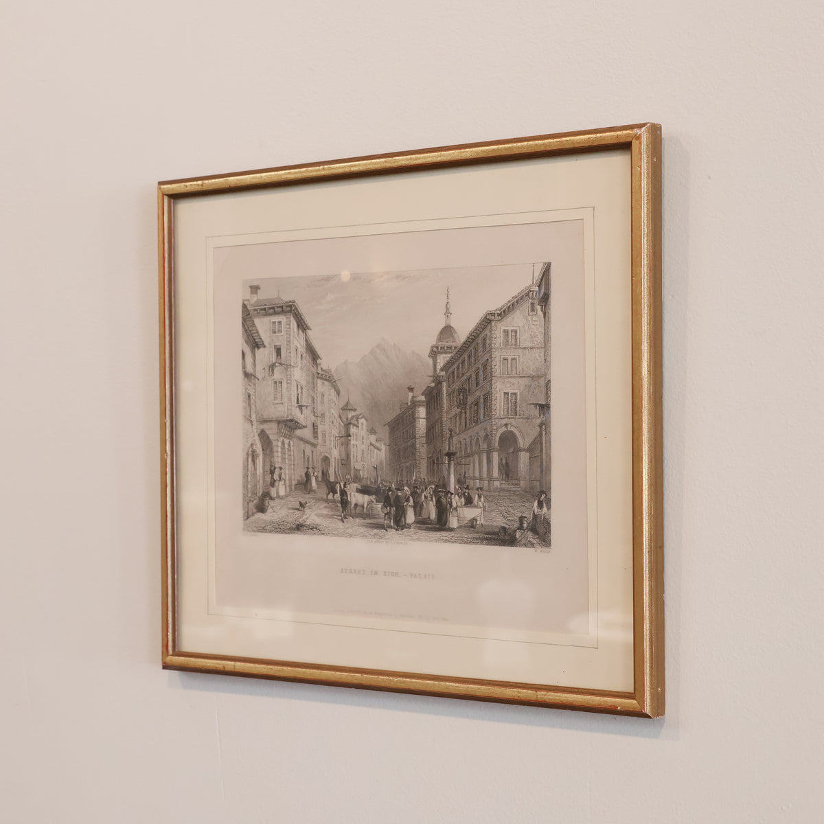 Framed black and white print of a city street scene on a beige wall.