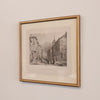 Framed black and white print of a city street scene on a beige wall.