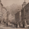 Vintage engraving of a bustling street scene with people and animals in an urban setting with mountains in the background.