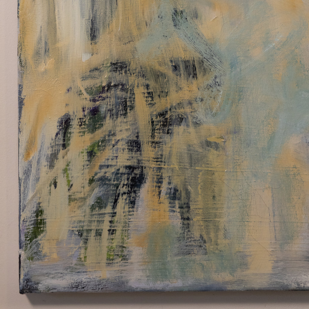 An abstract canvas painting featuring textured brushstrokes of muted yellow, pale blue, gray, and dark charcoal gray, shown hanging on a light beige wall.