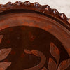 Close-up of a dark brown ceramic bowl or plate with a scalloped rim, featuring a painted snake and leaf motif in a glossy finish.