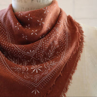 Brown patterned scarf wrapped around a cylindrical object with text on a white background