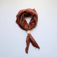 Brown bandana with white patterns on a light blue background