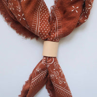 Brown bandana with white patterns on a light gray background