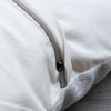 Close-up of a cream canvas zipperpered pouch or bag with a silver metal zipper pull, showing the texture of the fabric and the edge of the zipper tape.