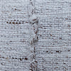 Close-up of a white woven textile with a vertical braided seam showing brown and white yarns.