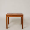 A square wooden table with a multi-panel checkered top and four straight legs, photographed against a neutral light gray studio background.