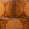Close-up of decorative ceramic tiles arranged in a 2x2 grid, featuring a warm brown and orange floral or leaf pattern with dark outlines.