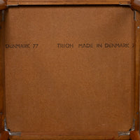 The back of a wooden framed picture or mirror, showing a brown textured backing board with metal corner brackets and printed text reading 'DENMARK 77' and 'TRIOH MADE IN DENMARK 77'.