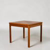 A mid-century modern square wooden side table with a geometric inlaid top and four tapered legs, shown on a light gray studio background.
