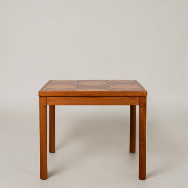 A square wooden table with a multi-panel checkered top and four straight legs, photographed against a neutral light gray studio background.