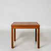 A square wooden table with a segmented top and four straight legs, photographed against a plain light gray studio background.