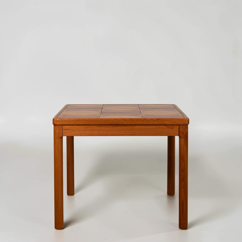 A square wooden table with a segmented top and four straight legs, photographed against a plain light gray studio background.