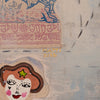 A close-up of a textured mixed-media painting featuring a stylized face with brown hair, pink cheeks, and a green star, alongside a patterned textile motif in pink and blue on a light gray canvas background.