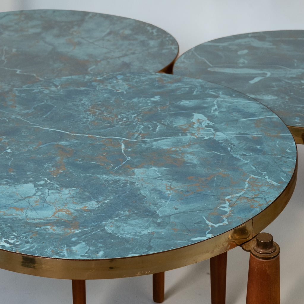 Round nesting tables with distressed blue-green marble tops and polished brass rims, supported by wooden legs.