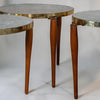 A set of round nesting tables with light gray marble-patterned tops and polished brass rims, supported by tapered medium-brown wooden legs.