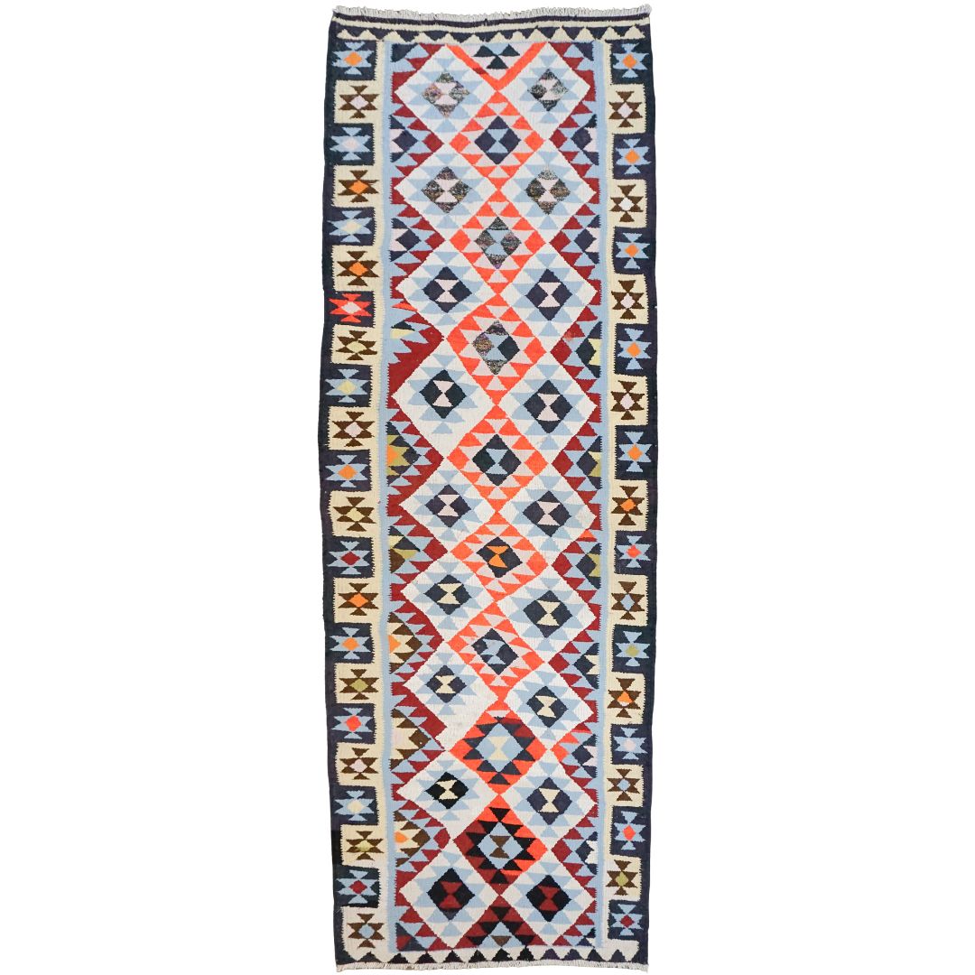 A long rectangular tribal-style runner rug with a geometric diamond pattern in red, navy, cream, and light blue, bordered on the sides with repeating star motifs.