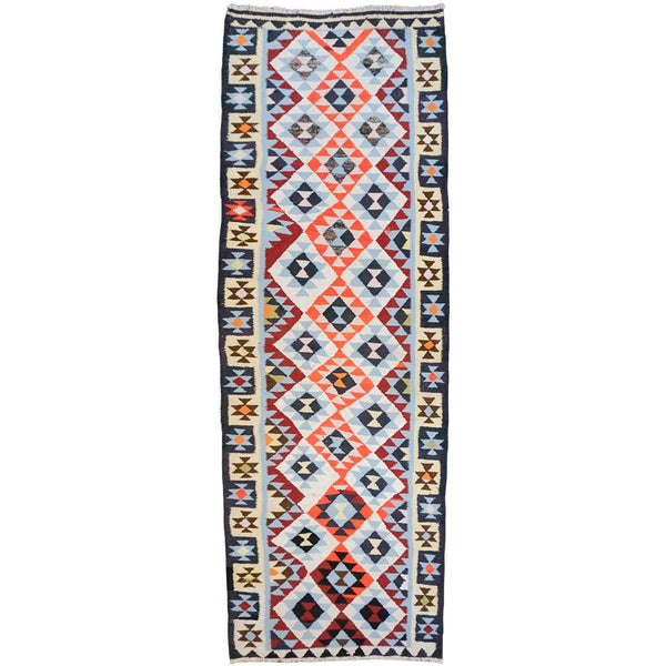 A long rectangular tribal-style runner rug with a geometric diamond pattern in red, navy, cream, and light blue, bordered on the sides with repeating star motifs.