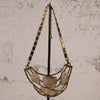 A vintage-style statement necklace with a gold-toned metal frame and five textured, organic-shaped clear resin or glass pendants, hanging on a black display stand against a textured beige wall.