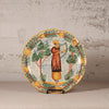 Decorative plate with a person playing a harp and surrounded by trees and birds on a textured wall background.