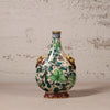 Decorative ceramic vase with green leaf patterns on a textured surface