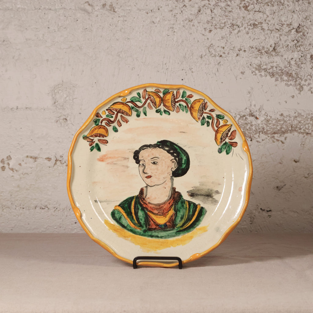 Ceramic plate with a decorative border and central portrait on a textured surface
