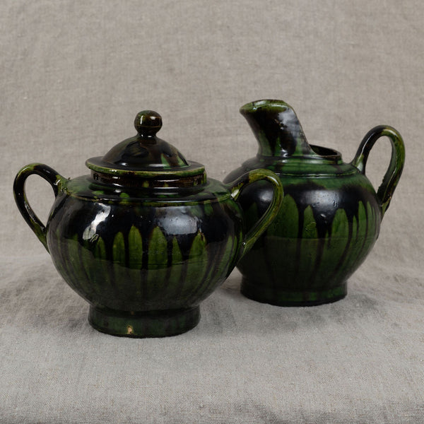 Two green ceramic pots on a textured beige surface