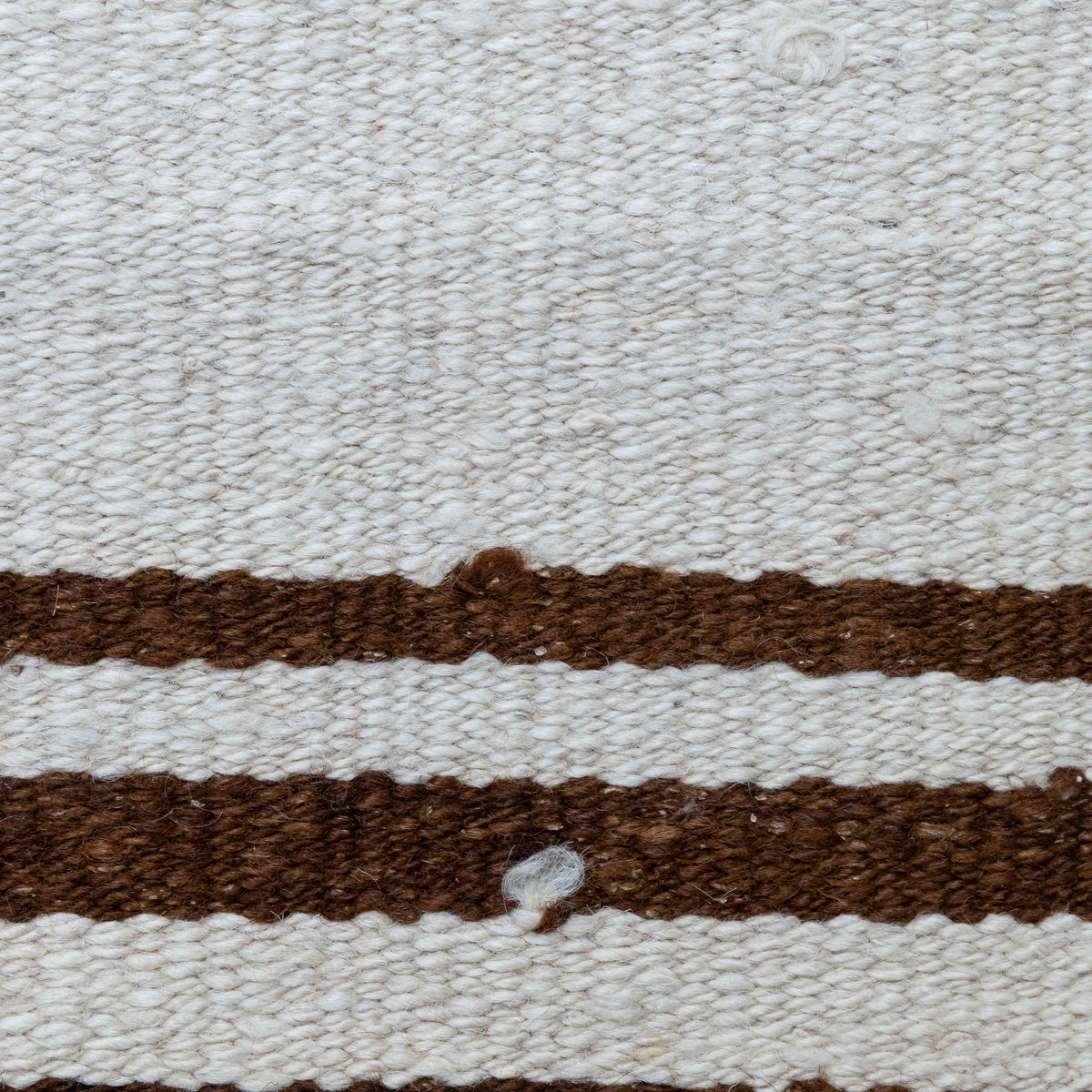 Close-up of a woven textile with a warm off-white background and two horizontal medium-brown stripes.