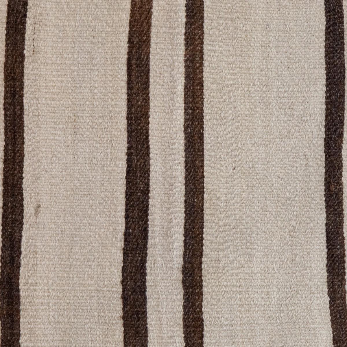 A close-up of a woven textile with a warm off-white or beige base and vertical dark brown stripes.