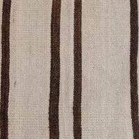 A close-up of a woven textile with a warm off-white or beige base and vertical dark brown stripes.