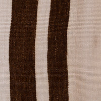 A close-up of a woven textile pattern featuring two vertical dark brown stripes on a warm beige background.