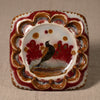 Decorative ceramic square plate with a bird design on a beige background
